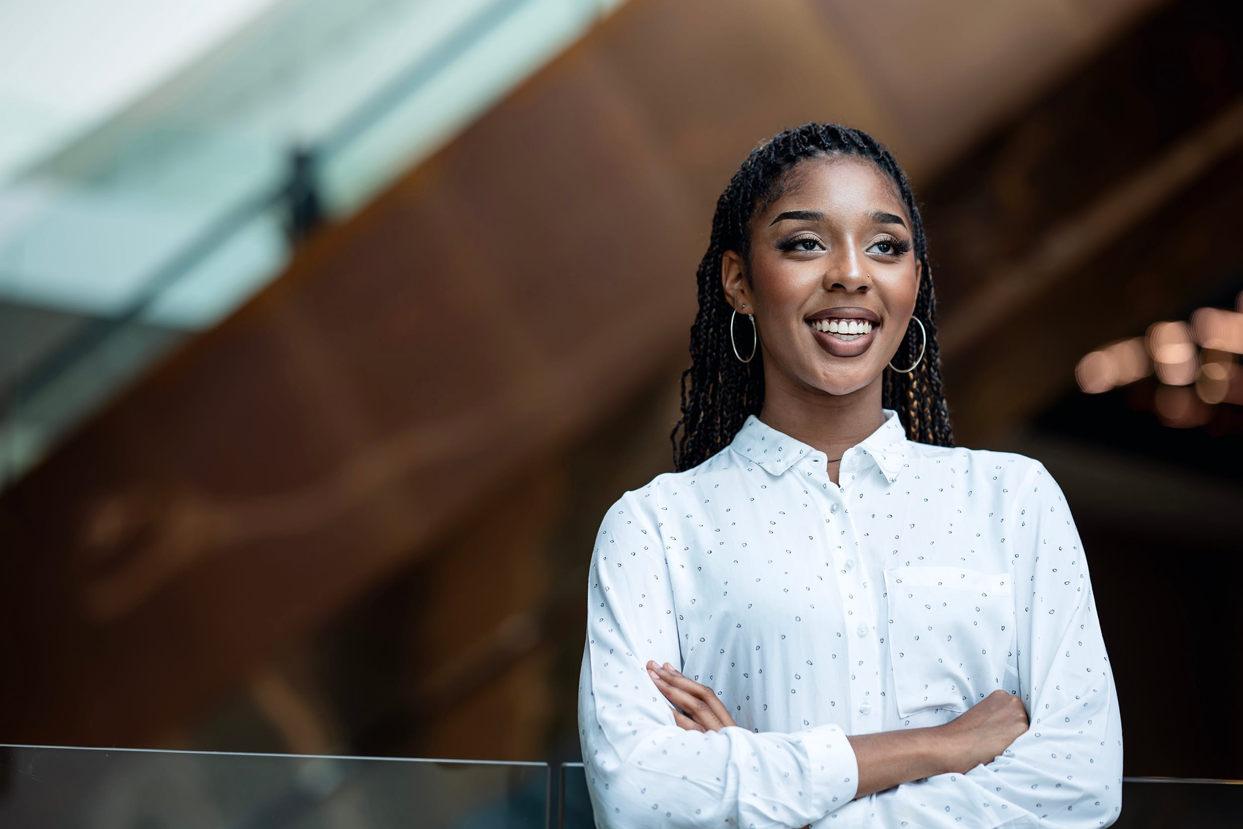 Keeping and Build Up Your Gen Zs Engaged On the Job. Proud of an African-American young businesswoman looking over the shoulder outside of a modern business office.